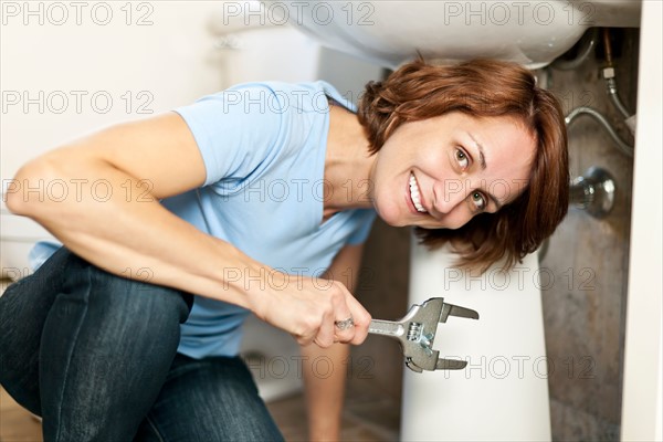 Woman plumbing in bathroom. Photo : Elena Elisseeva