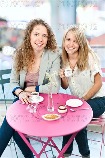 Two young women laughing in cafe. Photo : Elena Elisseeva