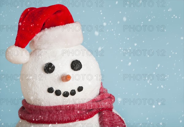Studio shot of snowman wearing Santa hat.