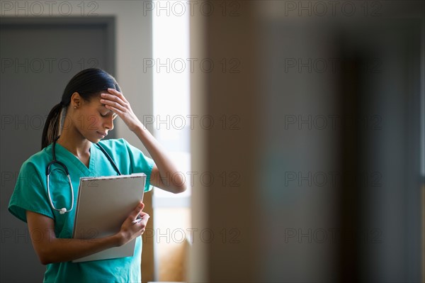 Female nurse with head in hands.