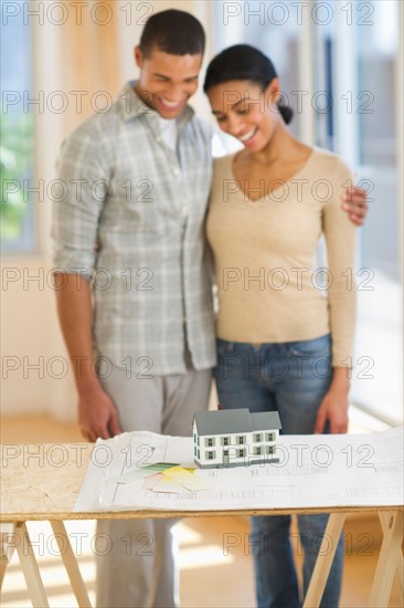 Couple looking at house blueprints and toy model.