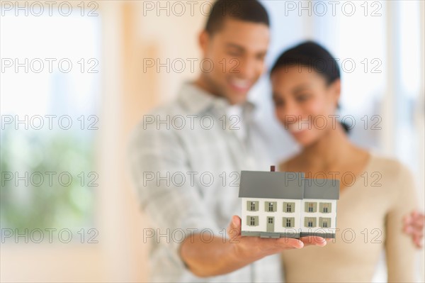 Couple holding toy house.