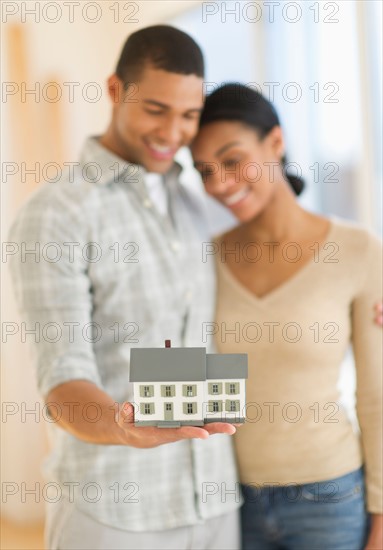 Couple holding toy house.