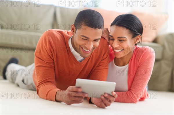 Couple lying on floor reading e-book.