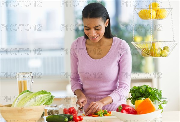 Woman chopping vegetables in kitchen.