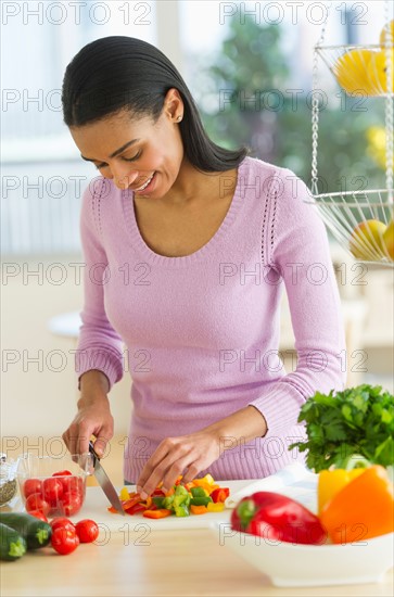 Woman chopping vegetables in kitchen.