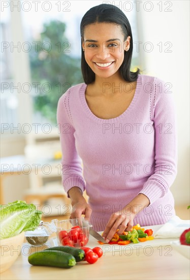 Portrait of woman chopping vegetables in kitchen.