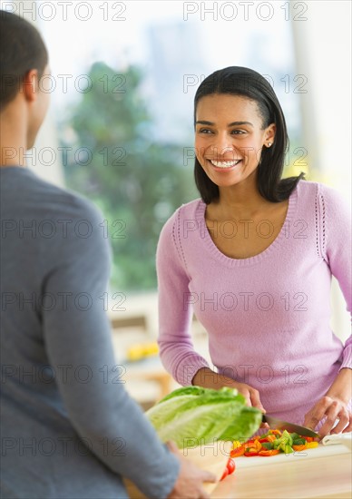 Couple chopping vegetables in kitchen.