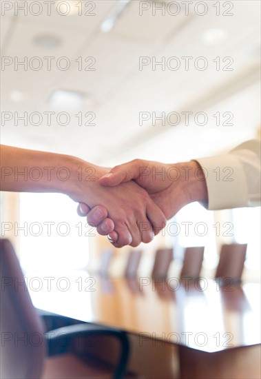 Close-up of business man and woman shaking hands.