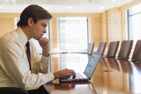 Businessman using laptop in board room.
