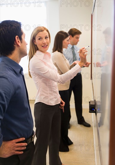 Business people writing at whiteboard.