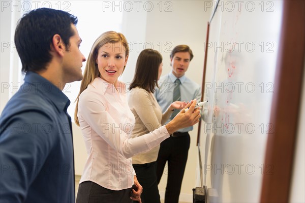 Business people writing at whiteboard.