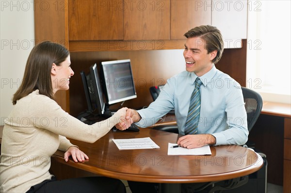 Businessman and client shaking hands in office.
