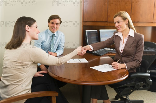 Businesswoman and clients shaking hands in office.