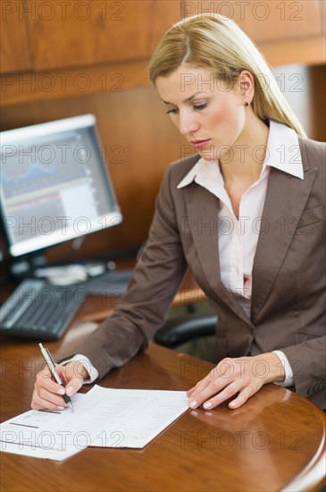 Businesswoman writing at desk.