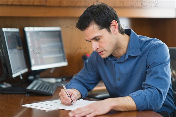 Businessman writing at desk.