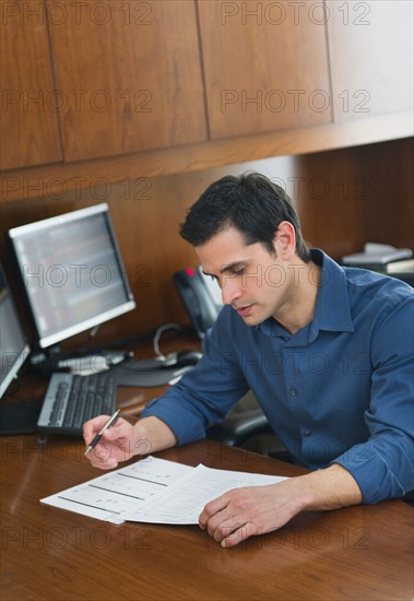 Businessman writing at desk.