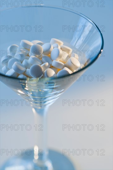 Martini glass filled with pills, studio shot.