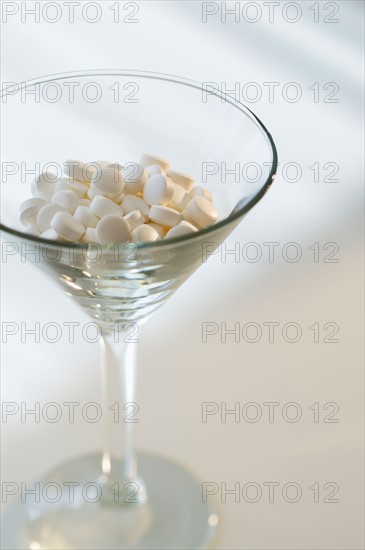 Martini glass filled with pills, studio shot.