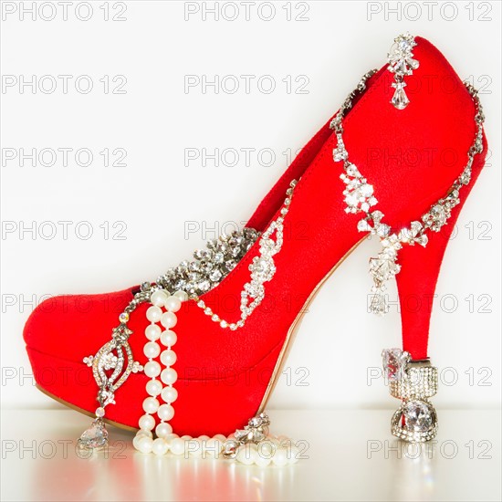 Studio shot of red stiletto with jewelry.