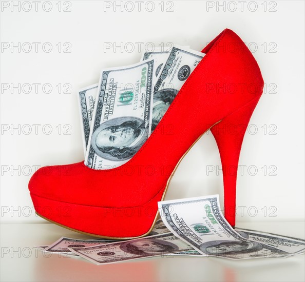 Studio shot of red stiletto and dollar bills.