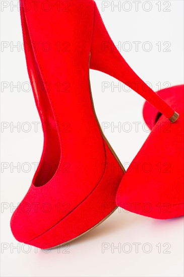 Pair of red stilettos on white background.