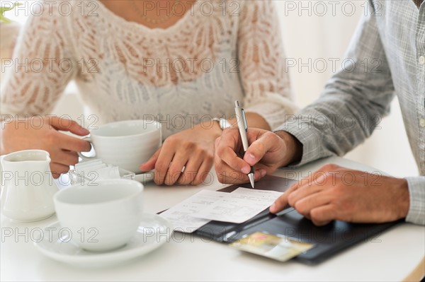 Couple enjoying tea, man signing receipt.