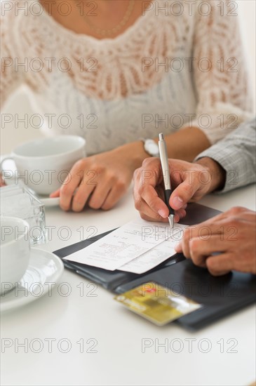 Couple enjoying tea, man signing receipt.