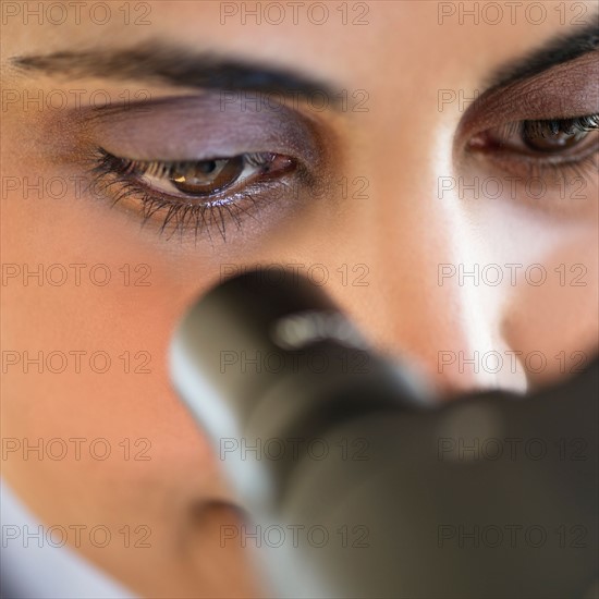 Scientist looking through microscope.