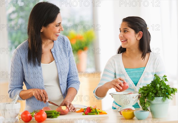 Mother and daughter (12-13) cooking in kitchen.