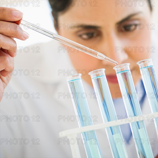 Scientist pipetting liquid into test tubes.