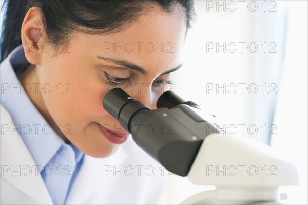 Scientist looking through microscope.