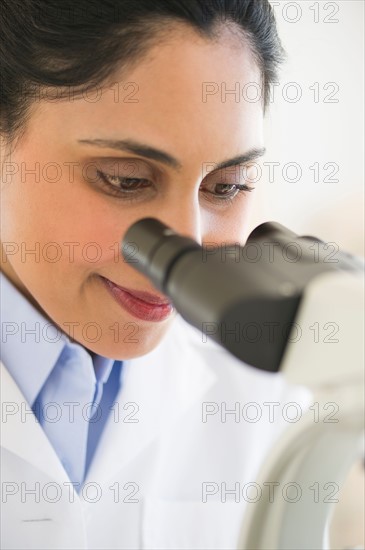 Scientist looking through microscope.