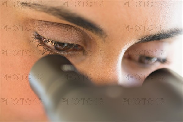 Scientist looking through microscope.