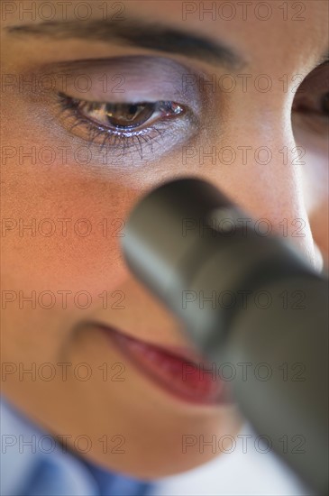 Scientist looking through microscope.