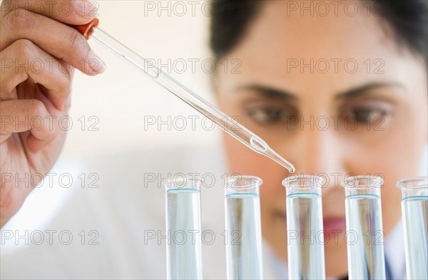 Scientist pipetting liquid into test tubes.