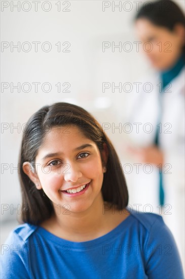 Portrait of girl  (12-13), doctor in background.