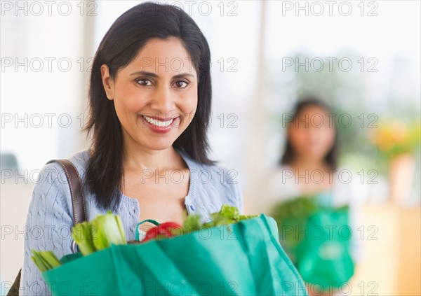 Woman holding bag of fresh vegetables.