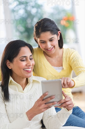 Mother and daughter (12-13) using digital tablet.