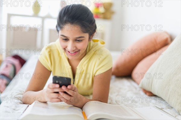 Girl (12-13) lying on bed and texting.