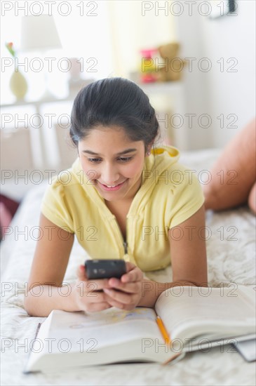 Girl (12-13) lying on bed and texting.