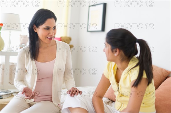 Mother and daughter (12-13) talking at home.