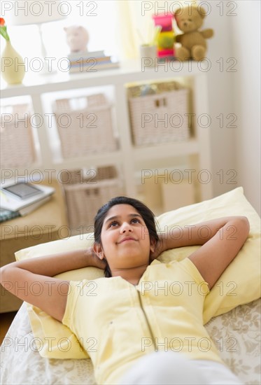 Girl (12-13) lying on bed.