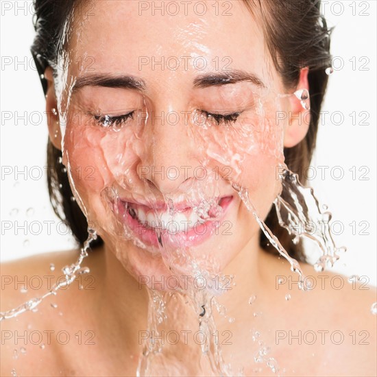 Studio shot of woman with splash of water on face.