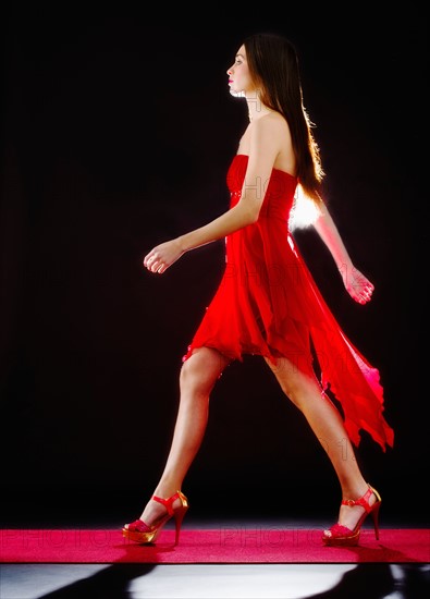 Woman wearing red dress on catwalk.