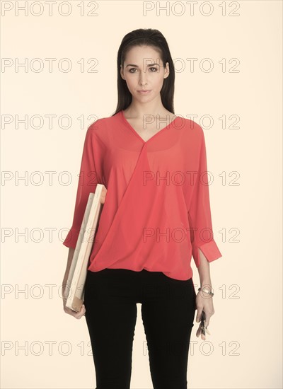 Studio shot of woman holding artist's canvas and paintbrushes.