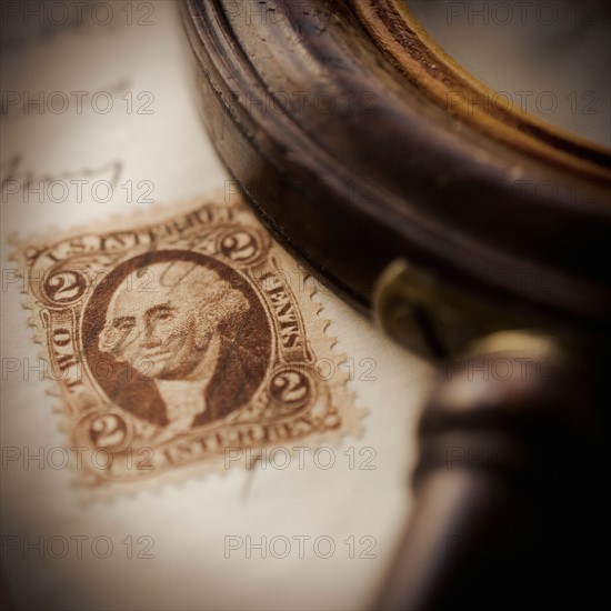 Studio shot of magnifying glass and old post stamp.
