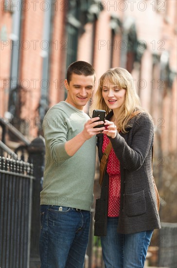 Couple using smart phone on street.