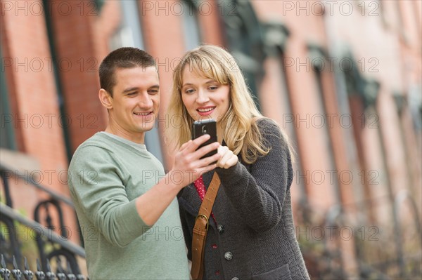 Couple using smart phone on street.