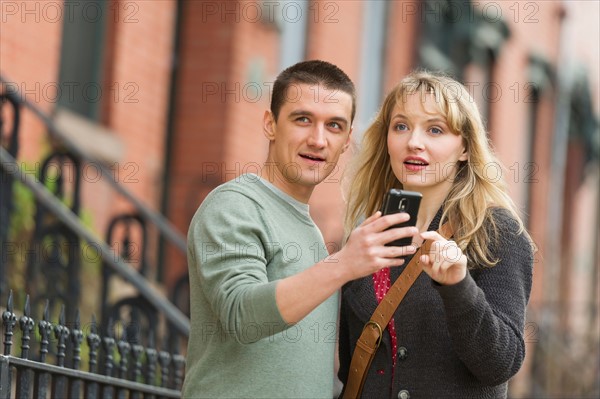 Couple using smart phone on street.
